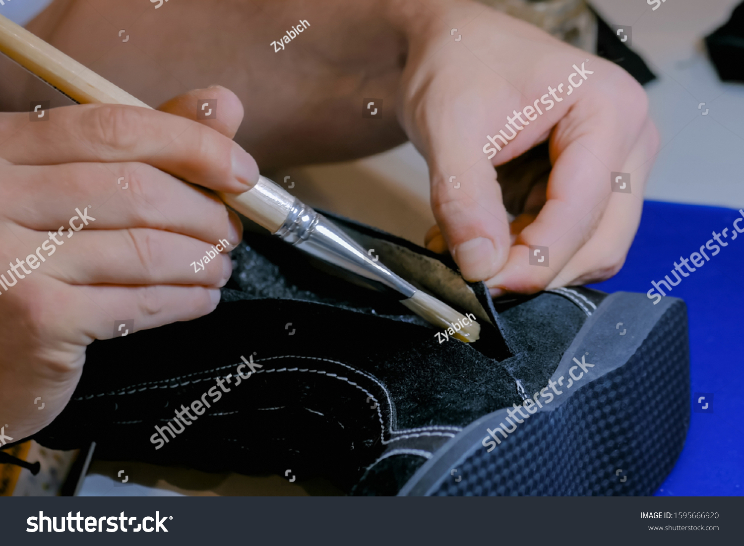 stock-photo-professional-man-shoemaker-cobbler-holding-brush-with-glue-and-repairing-black-female-boot-at-shoe-1595666920